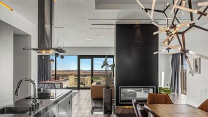 Una cocina moderna con una isla grande, un comedor con mesa de madera y vistas a un paisaje desértico a través de amplias ventanas.