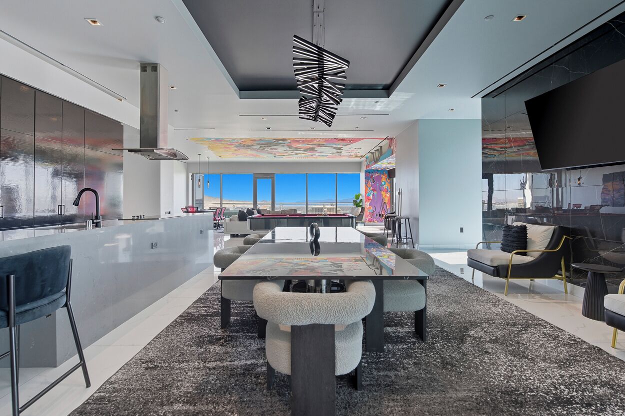 A modern kitchen with a large island, a dining area with a pool table, and a view of the ocean.