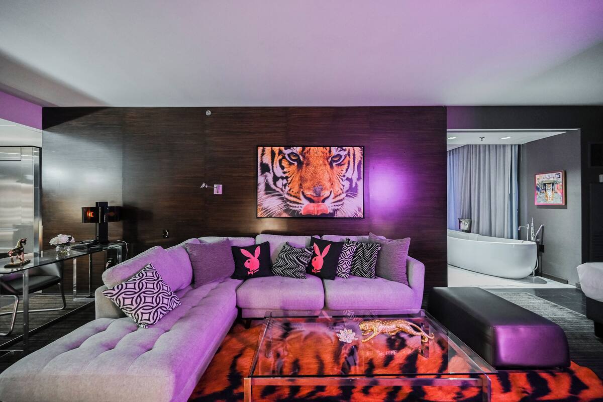 Un salon moderne avec un grand tableau représentant un tigre, un canapé gris et une table basse en verre.