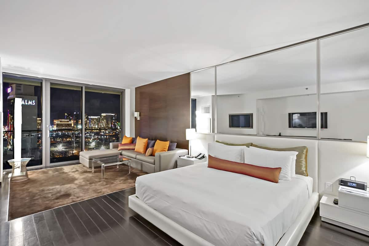 Une chambre d’hôtel moderne dotée d’un grand lit, d’un canapé, d’une télévision et offrant une vue sur la ville.