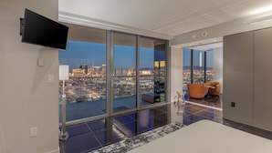 Una habitación de hotel moderna con un amplio ventanal corredero que da a un balcón con vistas a la ciudad.