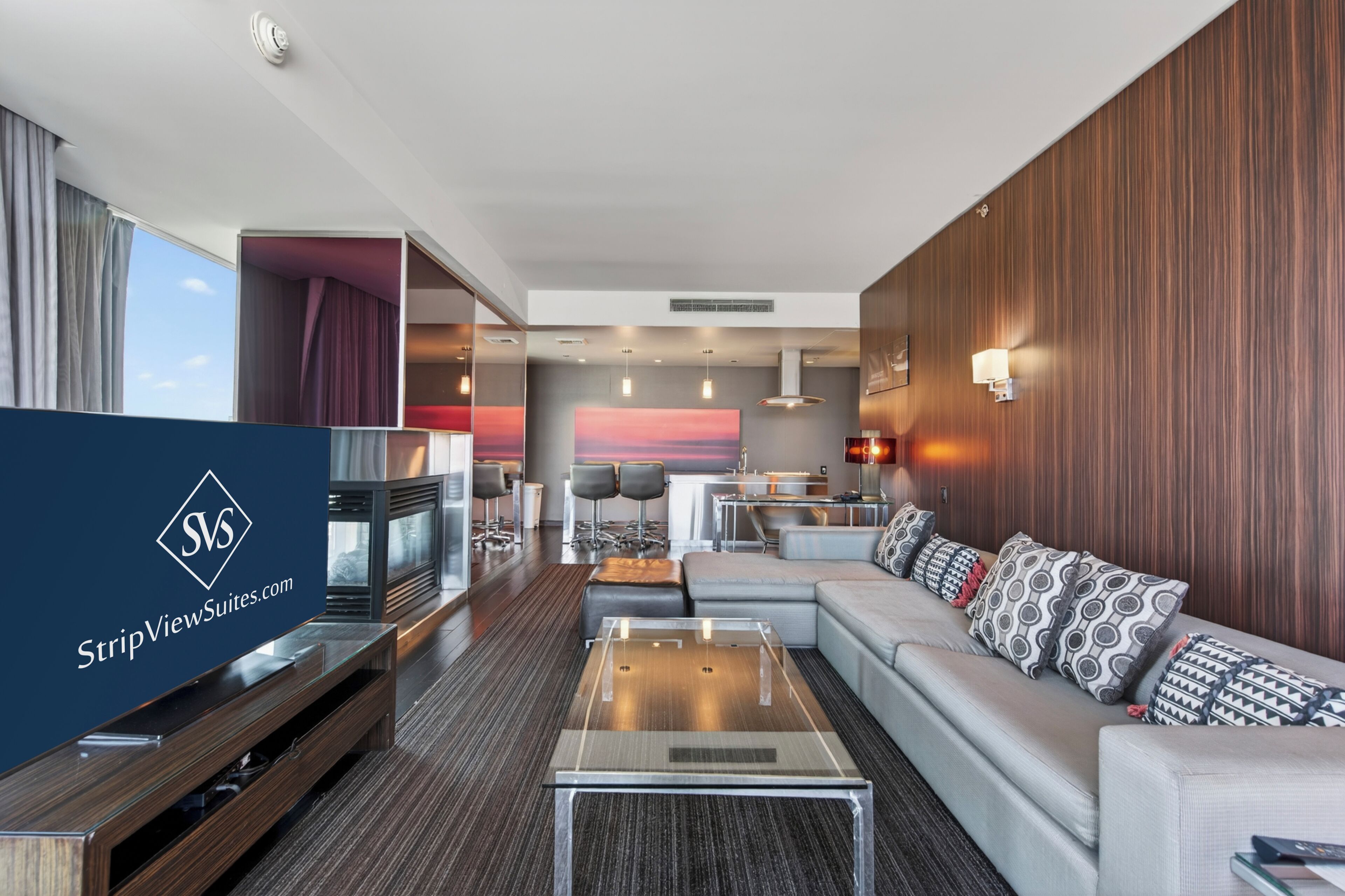 Ett modernt hotellrum med en soffa, ett soffbord, en TV och en matplats med stolar och ett bord.