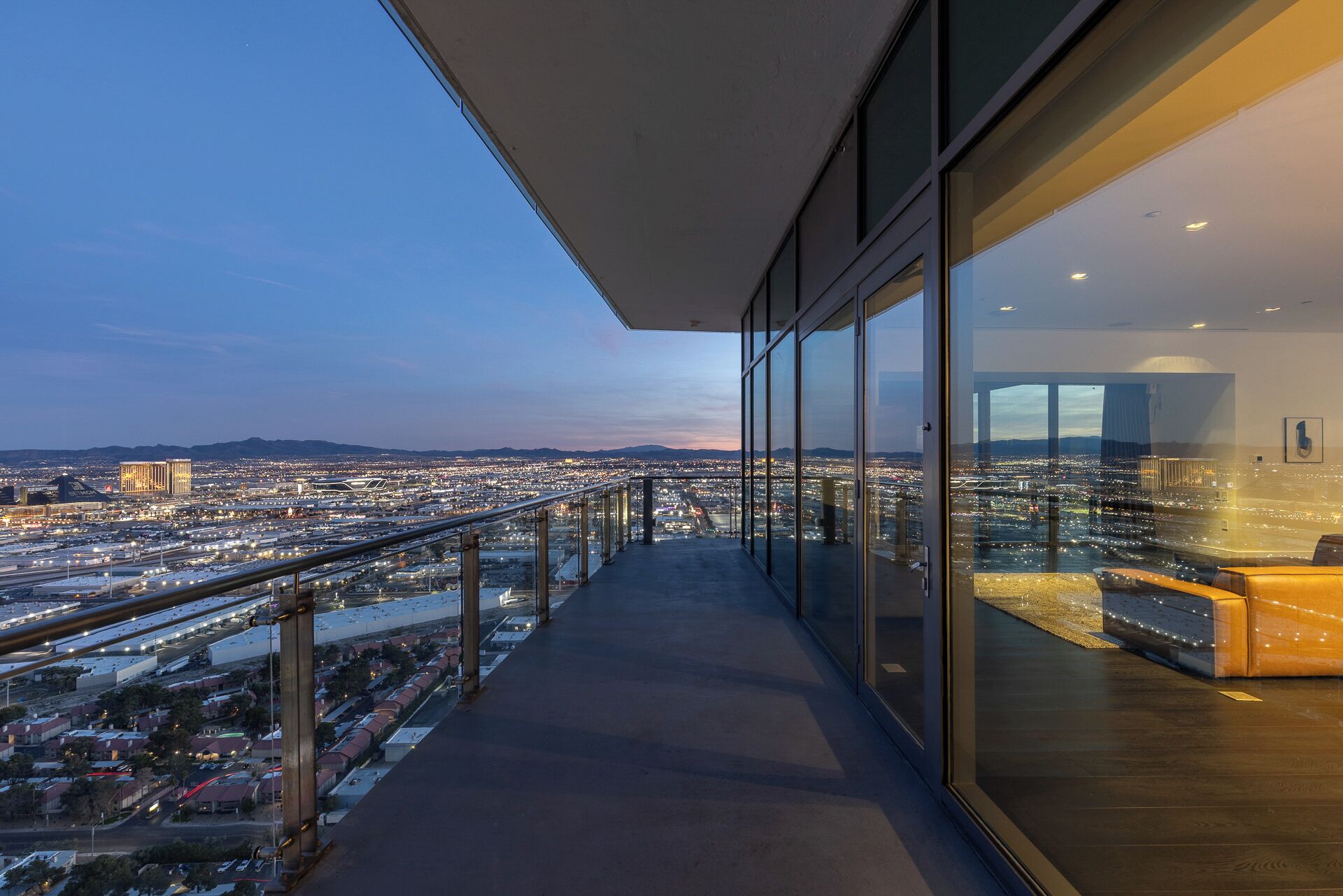 Un edificio alto con balcón que da a una vista panorámica de la ciudad al atardecer.