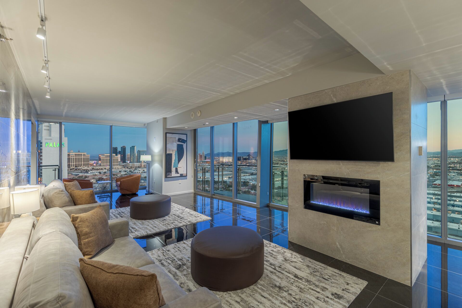 A modern living room with a large TV, a fireplace, and a city view.