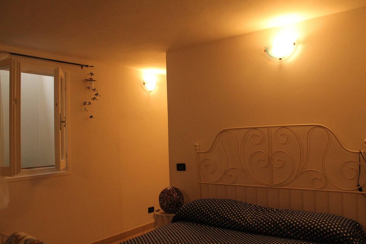Une chambre à coucher avec un lit, une fenêtre et des lampes fixées au mur.