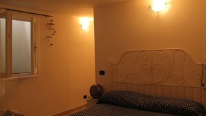 A bedroom with a bed, a window, and wall-mounted lights.