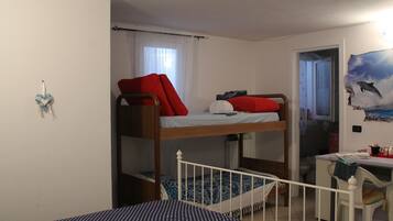 Cozy retreat with a bunk bed setup, compact desk area, and wall-mounted shelf for added storage.
