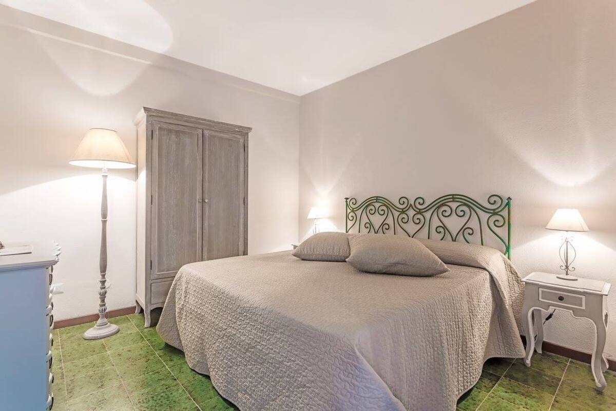 A bedroom with a bed, two bedside lamps, a wardrobe, and a floor lamp.