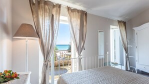 A bedroom with a bed, curtains, a lamp, and a view of the sea. - Torre S.Antonio (Santa Caterina dello Ionio)