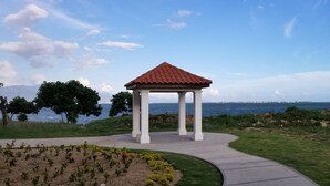 A gazebo with a red roof and white columns, surrounded by a landscaped garden and a view of the sea. - Sunrise Villa On The Beach (Portmore)