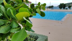 A swimming pool with a view of the sea and a building in the background. - Sunrise Villa On The Beach (Portmore)