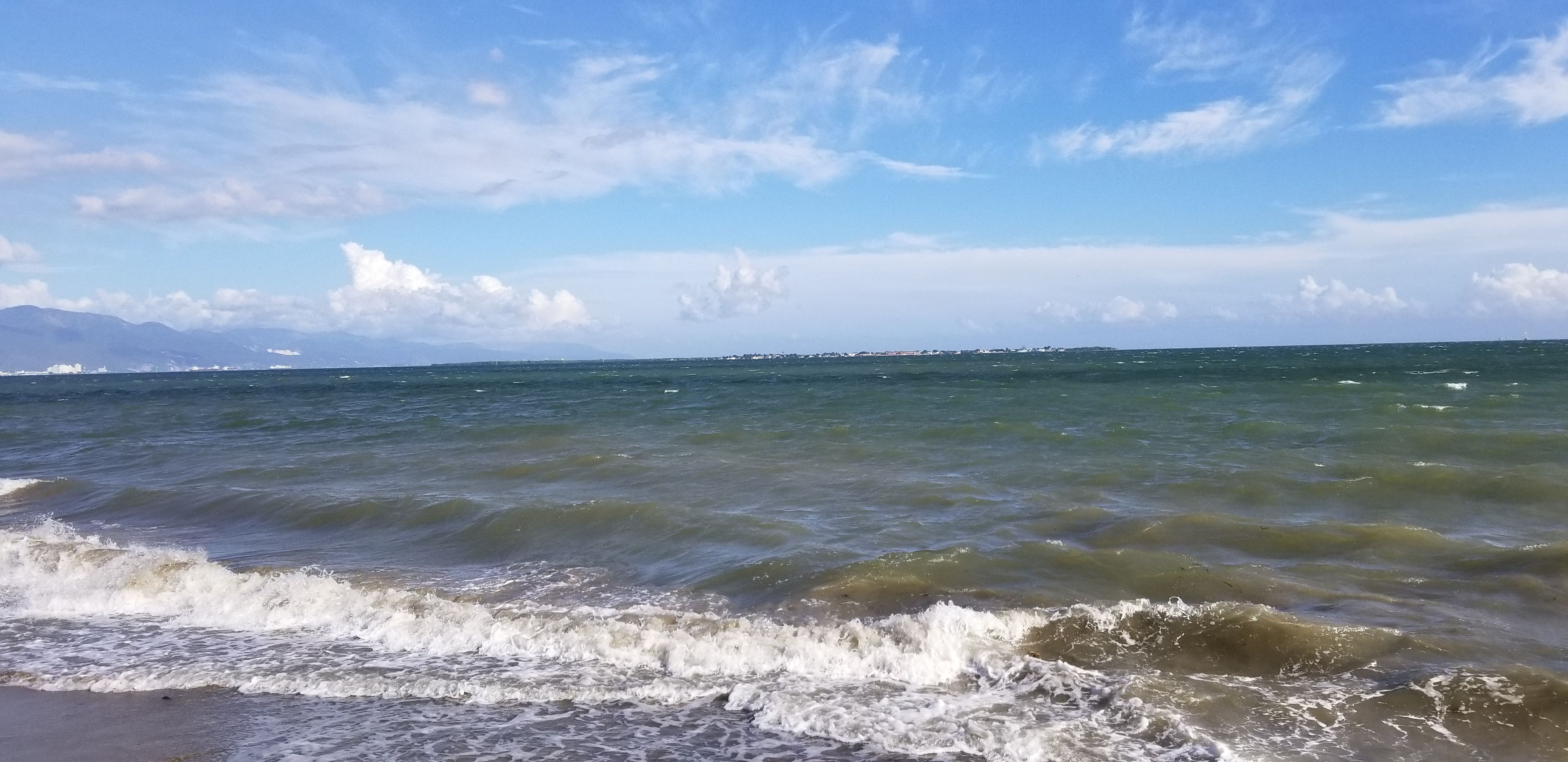 A beach with waves and a clear sky.