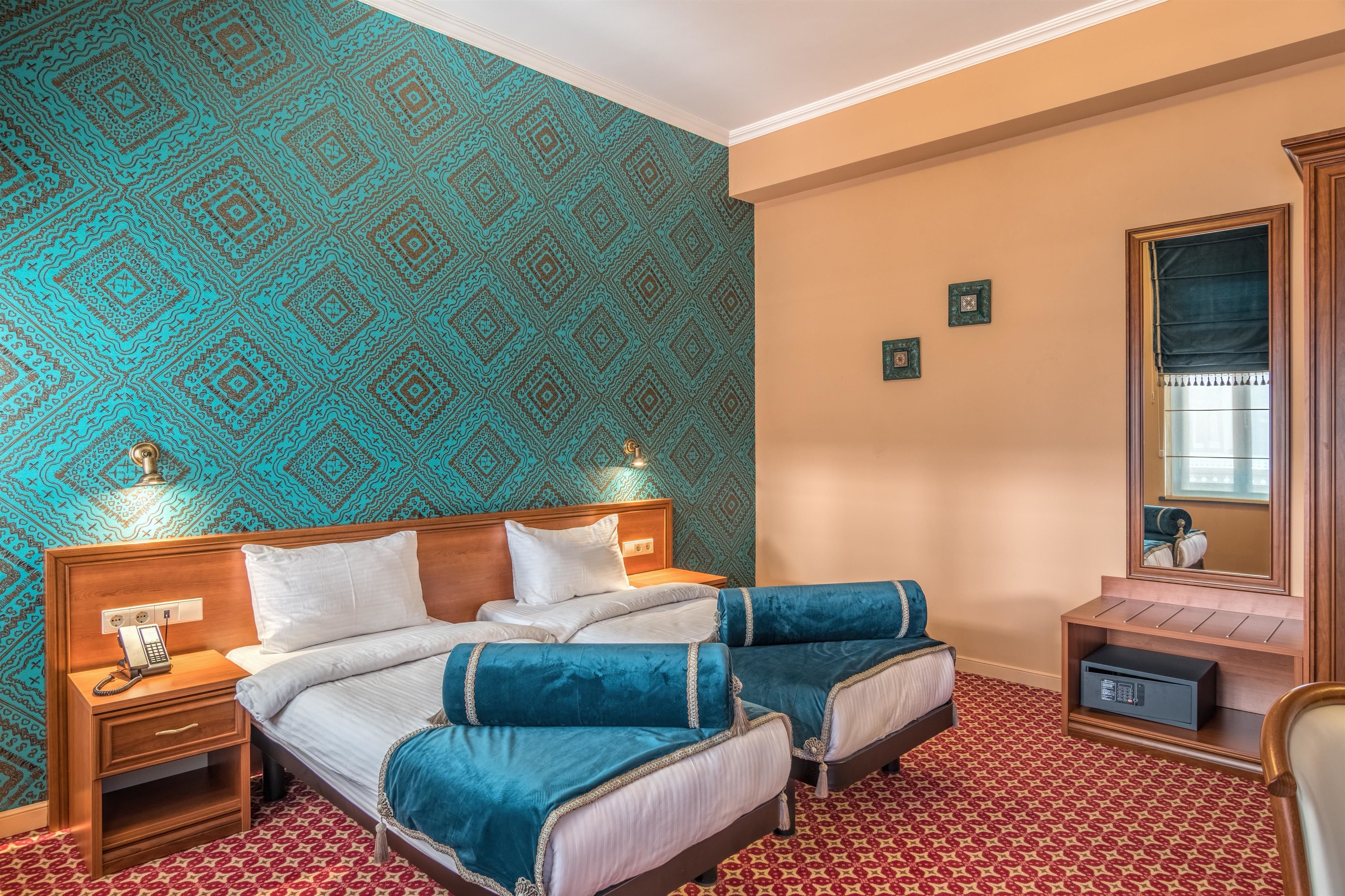Une chambre d’hôtel avec deux lits, une table de chevet avec un téléphone, un miroir et une petite armoire.