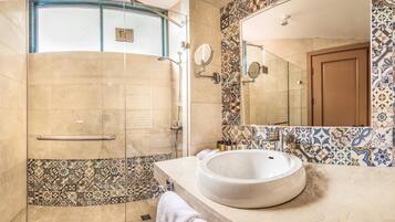Un baño con ducha de vidrio, un espejo grande y un lavabo blanco.