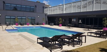 Una piscina al aire libre, sillones reclinables de piscina