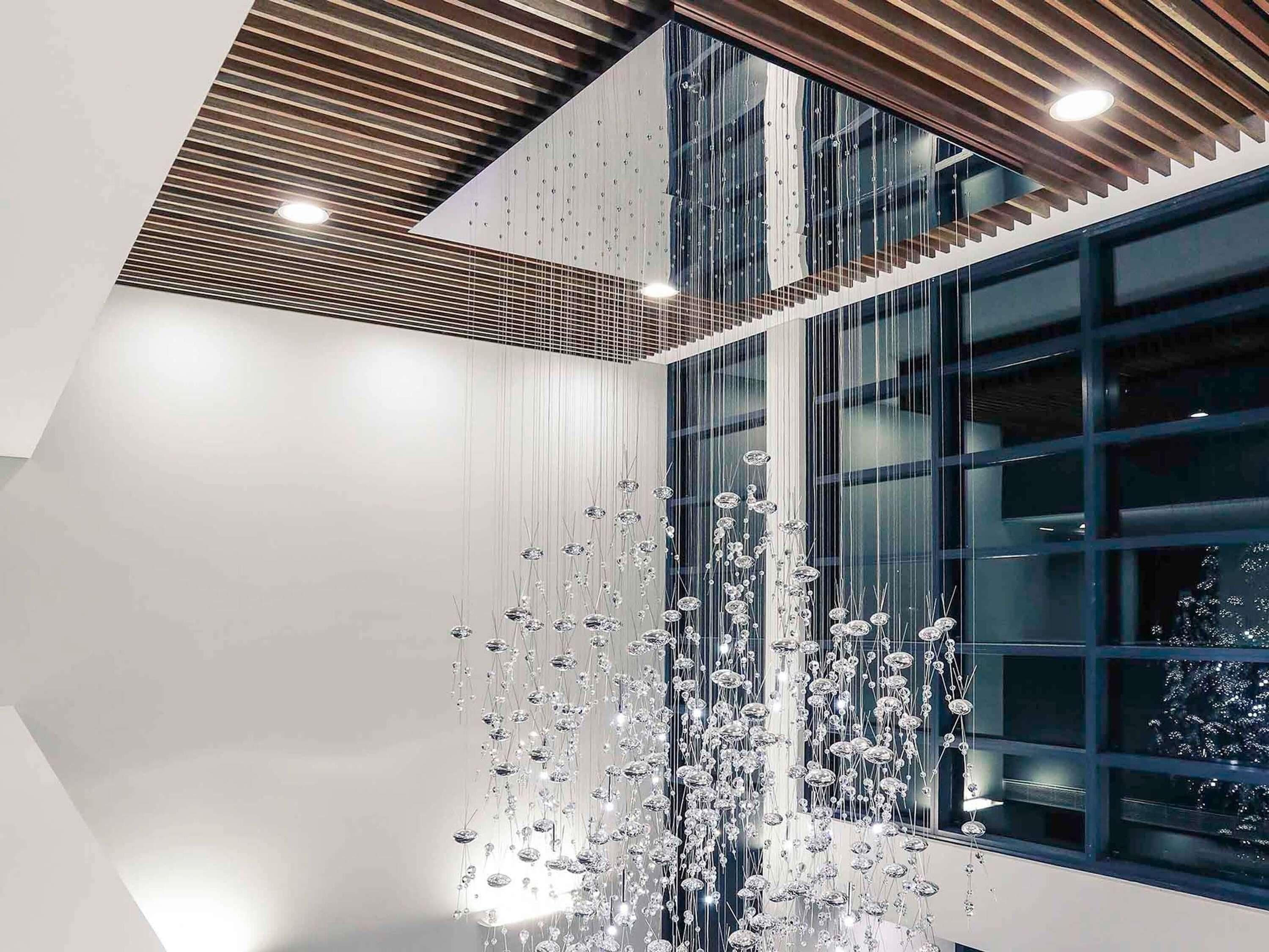 Un intérieur moderne avec un plafond haut, des surfaces réfléchissantes et un escalier.