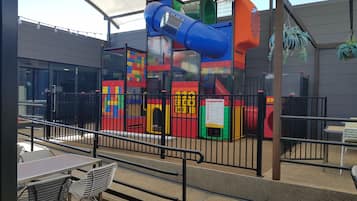 Children can play safely in this enclosed outdoor space featuring a colorful play structure with a slide and climbing elements.