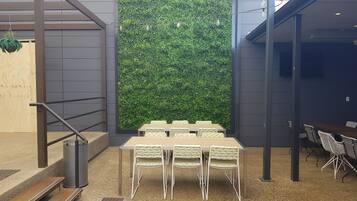 A modern indoor space with a green wall, a wooden staircase, and a table with chairs.