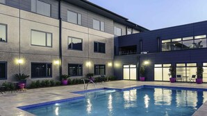 A modern building with a swimming pool, outdoor seating, and potted plants. - Mercure Tamworth (West Tamworth)