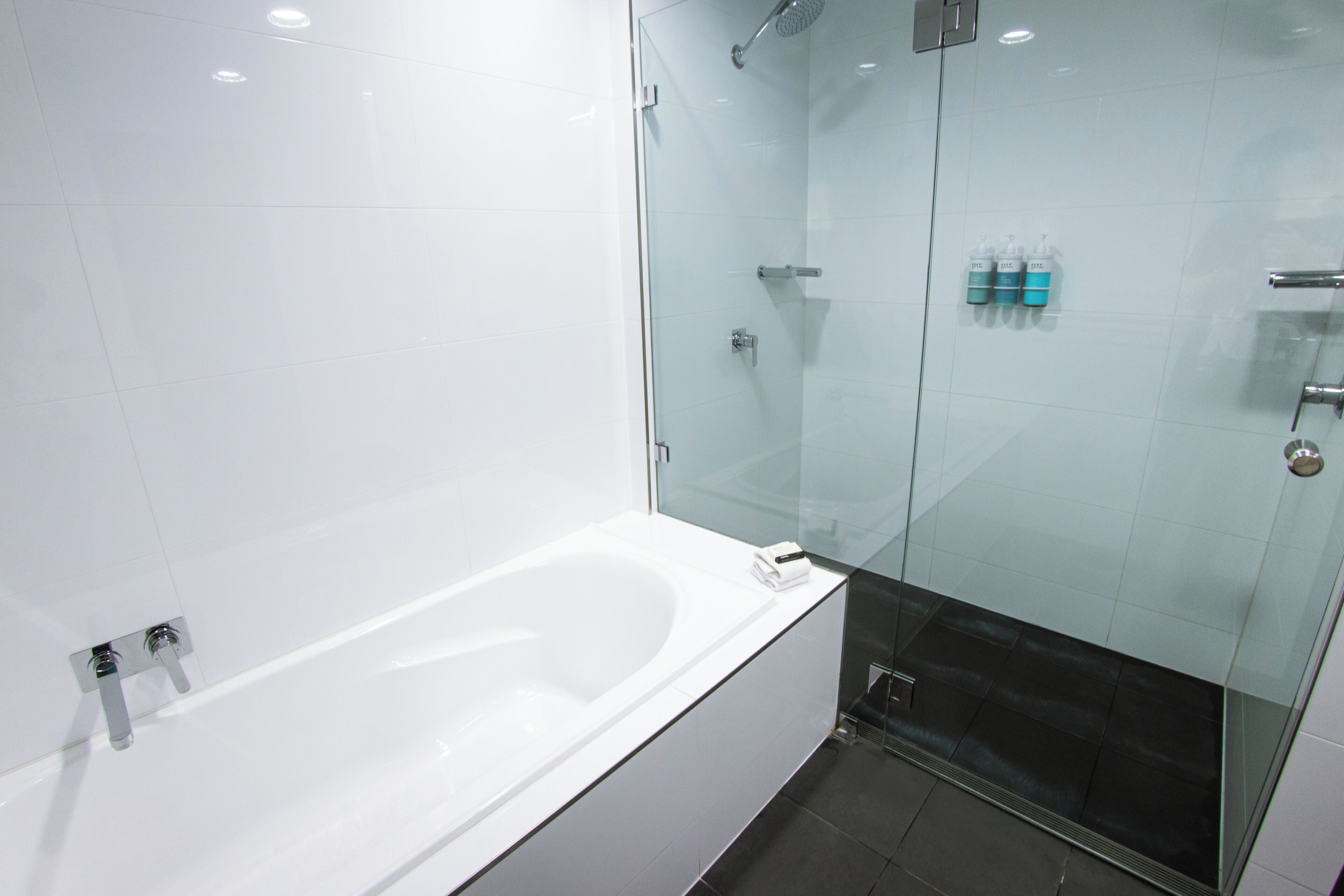 Un baño moderno con una bañera blanca, cabina de ducha con paredes de vidrio y separador de vidrio.