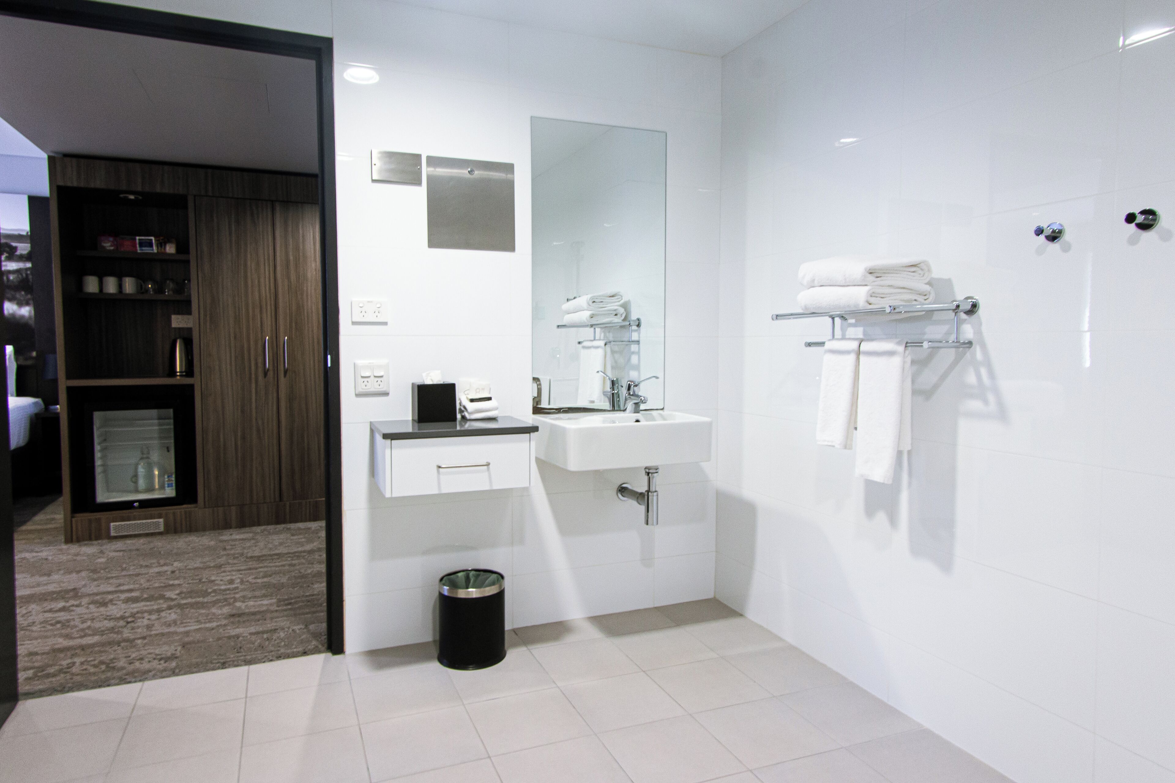 Une salle de bain moderne avec un lavabo, un miroir et un porte-serviettes.