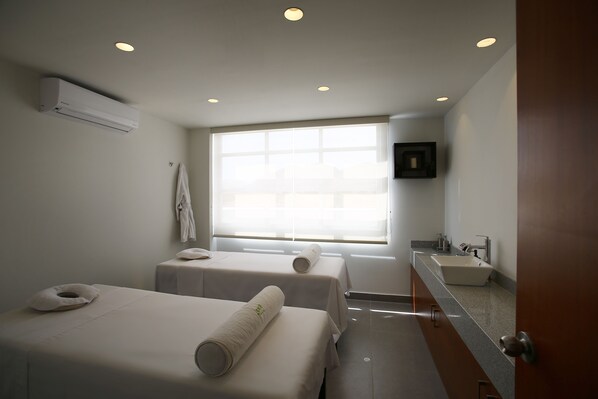 A modern hotel room with two beds, a large window, a bathroom with a sink, and an air conditioning unit. - Casa Andina Select Moquegua (Moquegua)