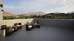 Una terraza con mobiliario de mimbre y vistas a las montañas.
