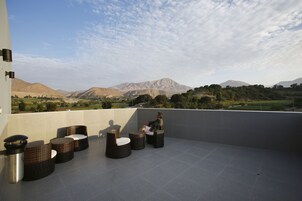 Una terraza con mobiliario de mimbre y vistas a las montañas.