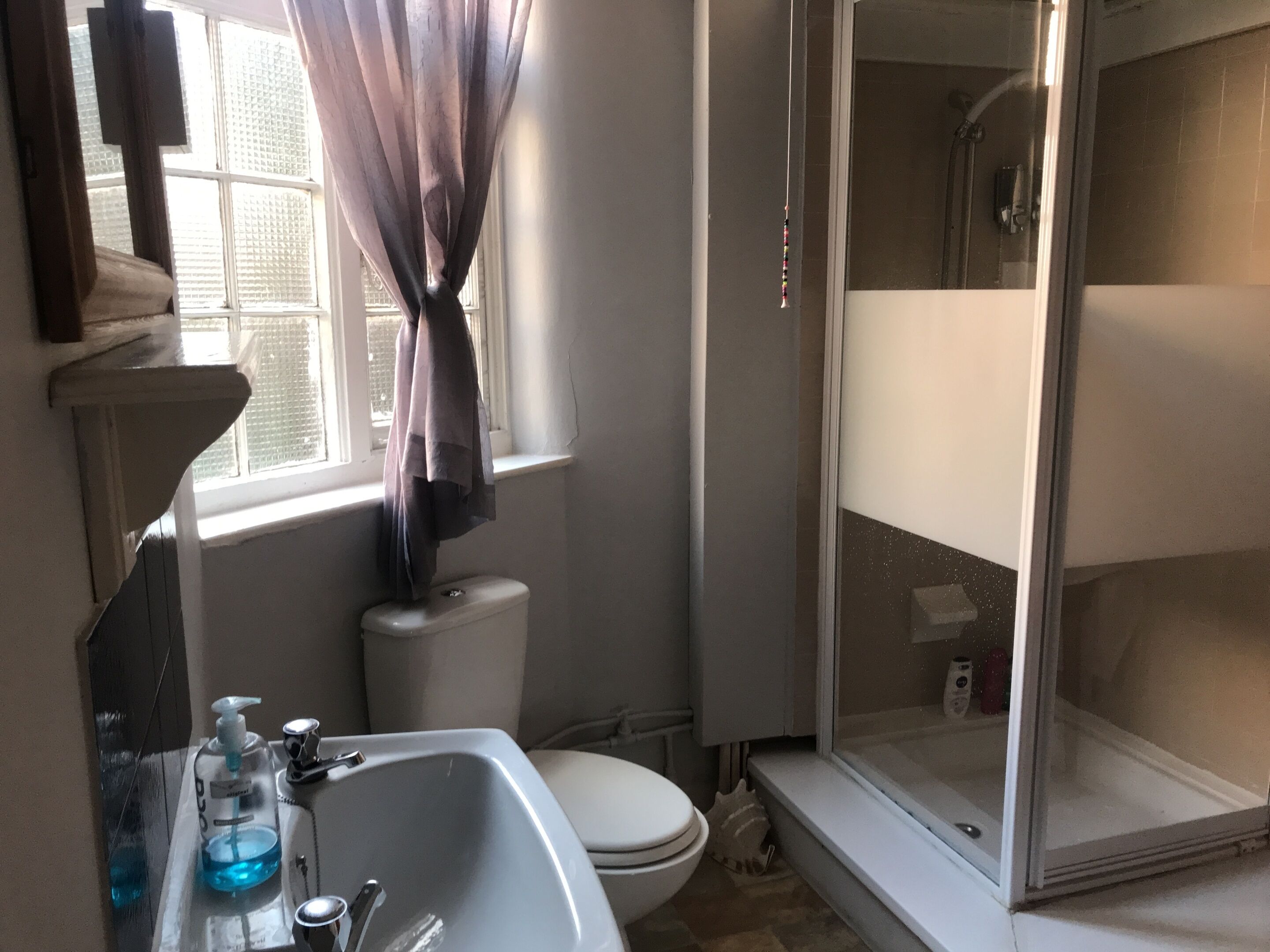Un baño con lavamanos blanco, inodoro y cabina de ducha de vidrio.