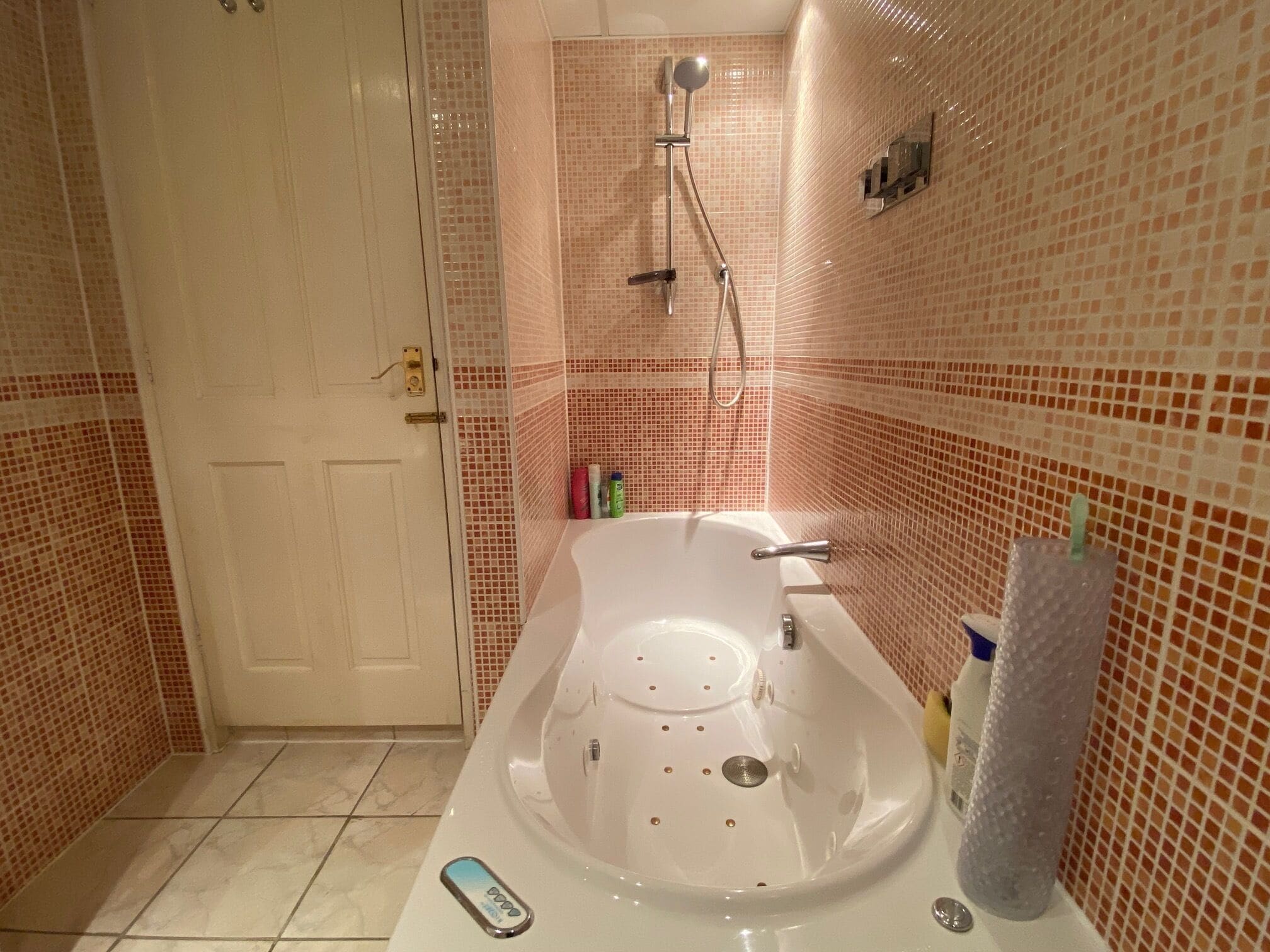 A bathroom with a white bathtub, a shower, and tiled walls.
