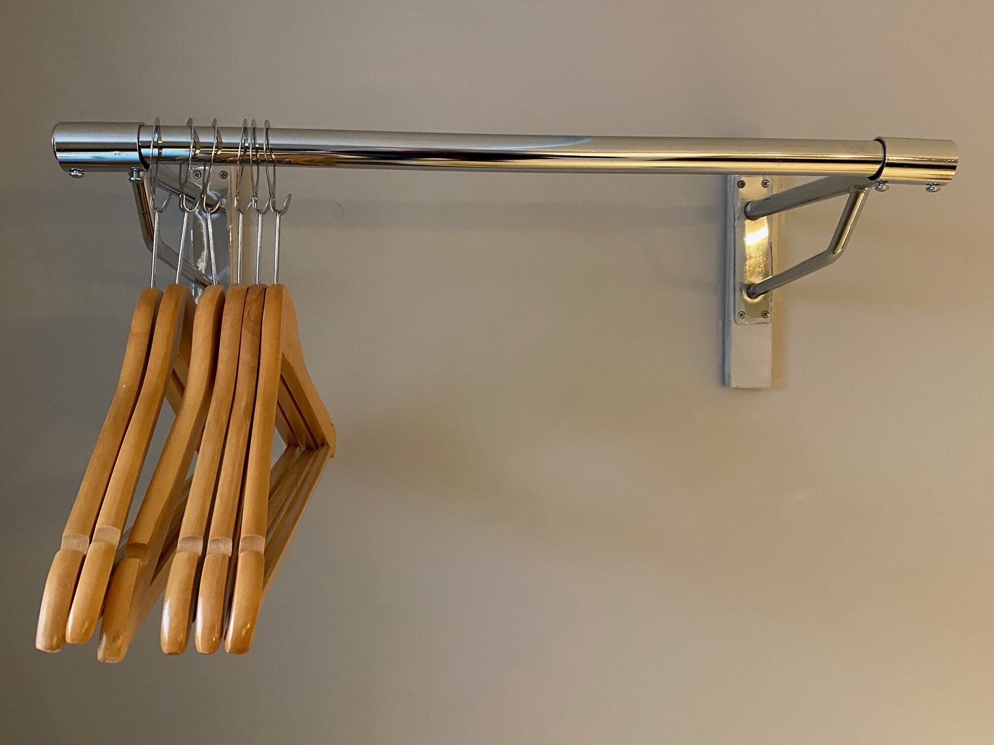 A metal curtain rod with wooden hangers.