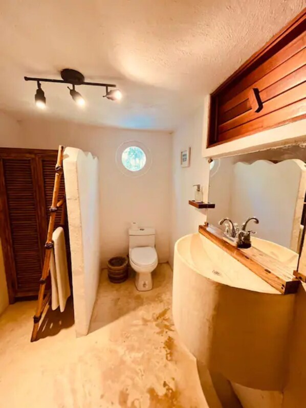Un baño con tocador de madera, inodoro y zona de ducha.