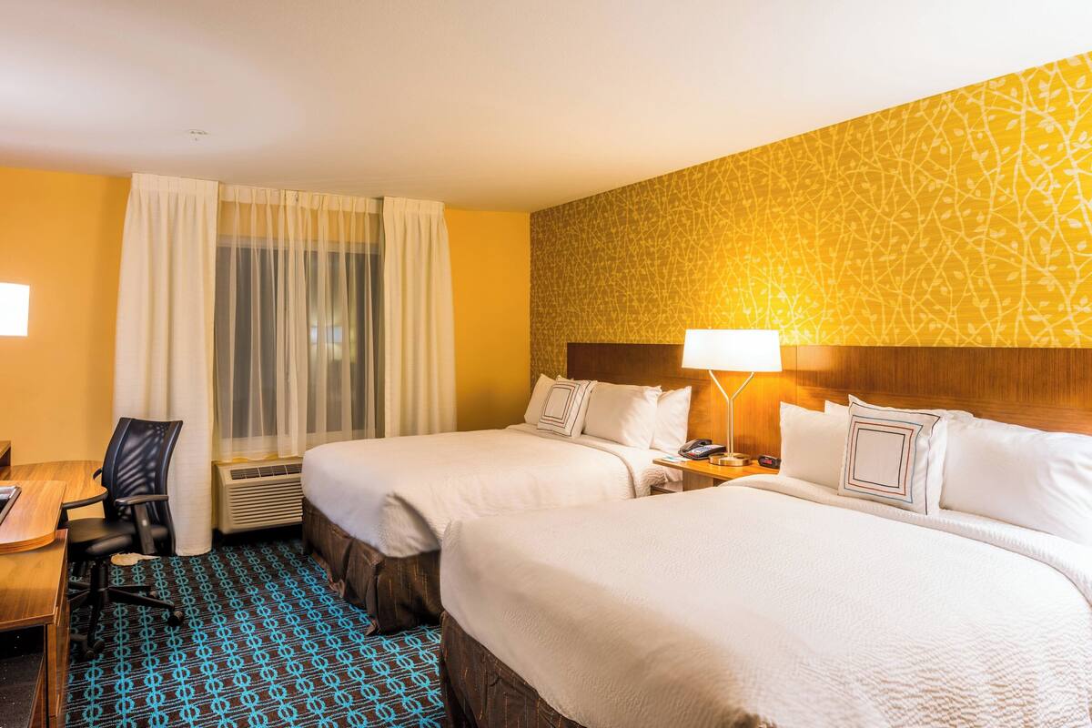 Une chambre d’hôtel avec deux lits, un bureau et une chaise.