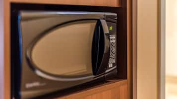 A microwave oven with a digital display and control panel, housed in a wooden cabinet.