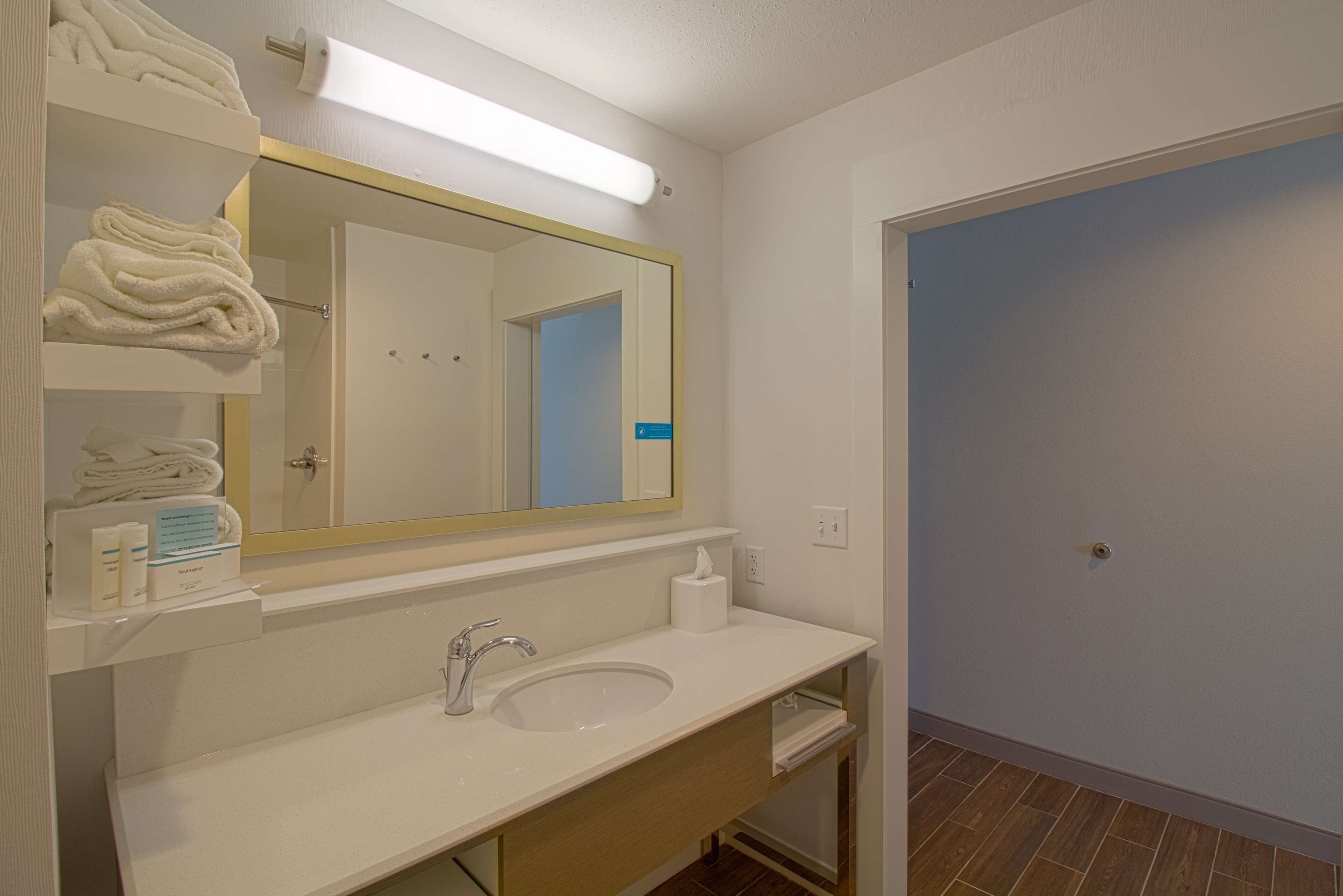 Een badkamer met een witte wasbak, een spiegel en een handdoekhouder.
