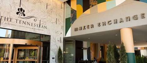 Entrada de un hotel con fachada de mármol, puerta giratoria y un cartel que dice 'The Tennesseean Personal Luxury Hotel & Residences'.
