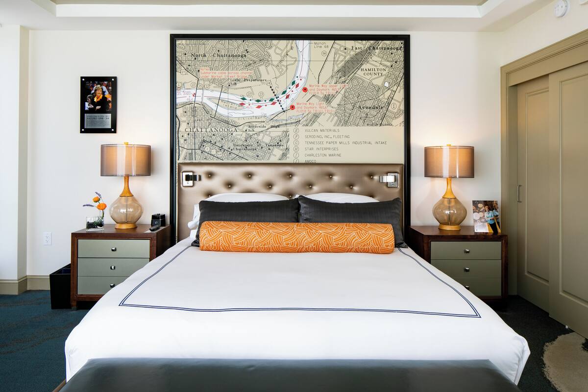 A hotel room with a large bed, two nightstands, a map on the wall, and a framed picture.