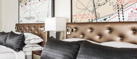 A hotel room with a large bed, two nightstands, a lamp, and two large maps on the wall.