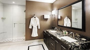 Une salle de bain moderne avec une douche en verre, un grand miroir et des meubles en bois foncé.
