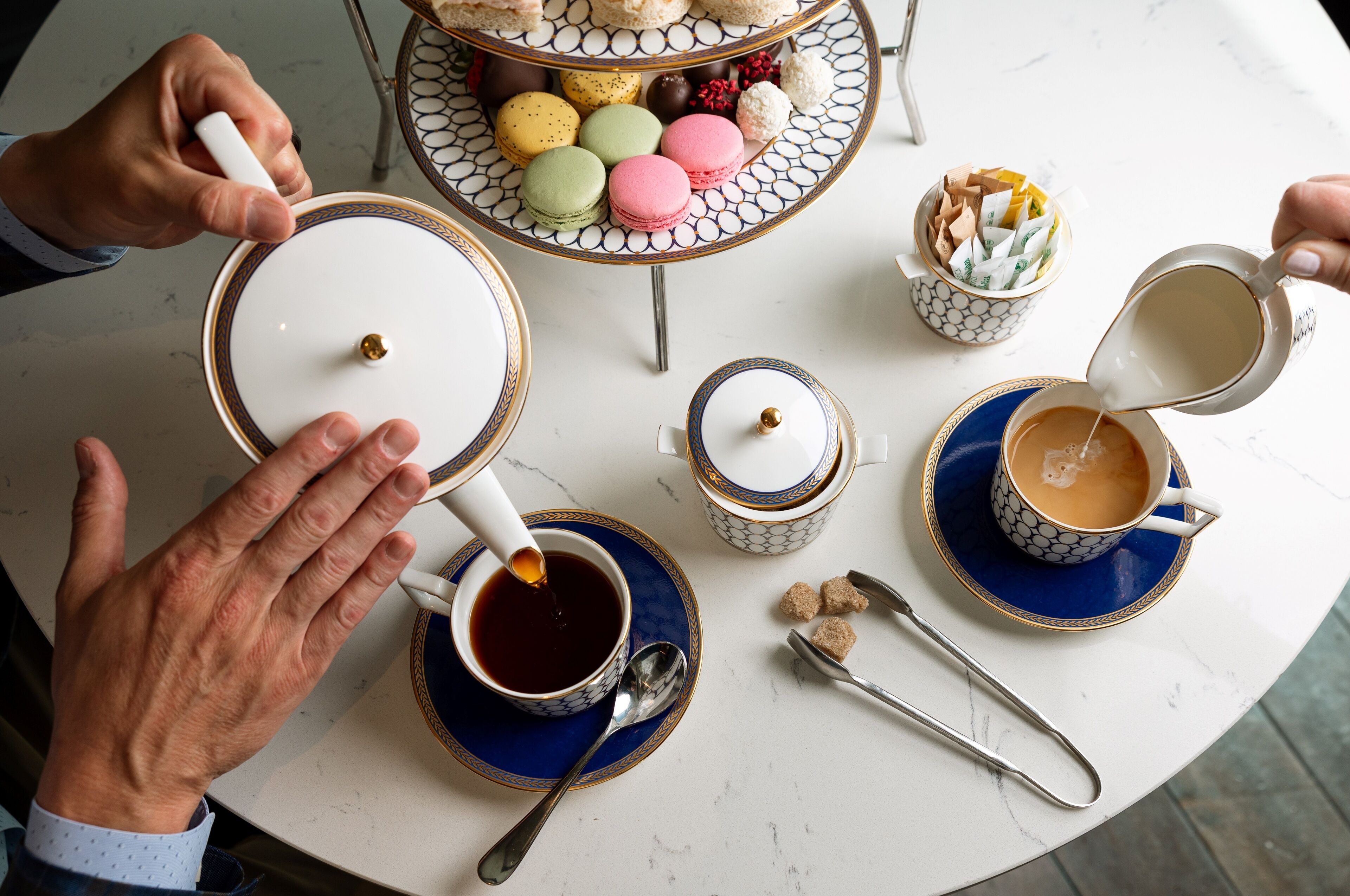 A table with various items including cups of coffee, macarons, and a decorative plate.