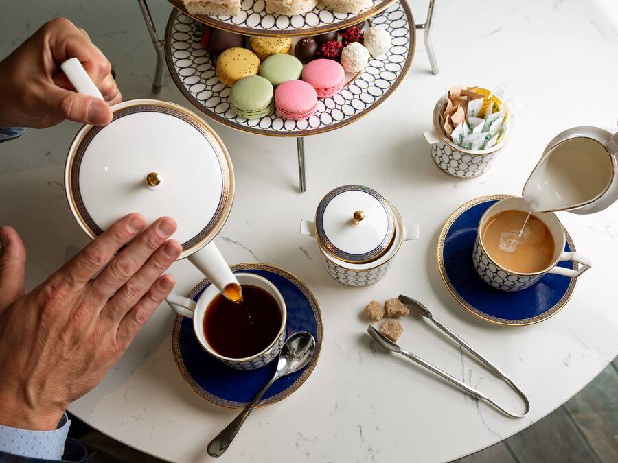 A table with various items including cups of coffee, macarons, and a decorative plate.