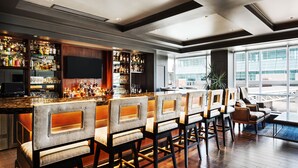 A bar area with multiple seating options, a well-stocked bar, and large windows offering a view.