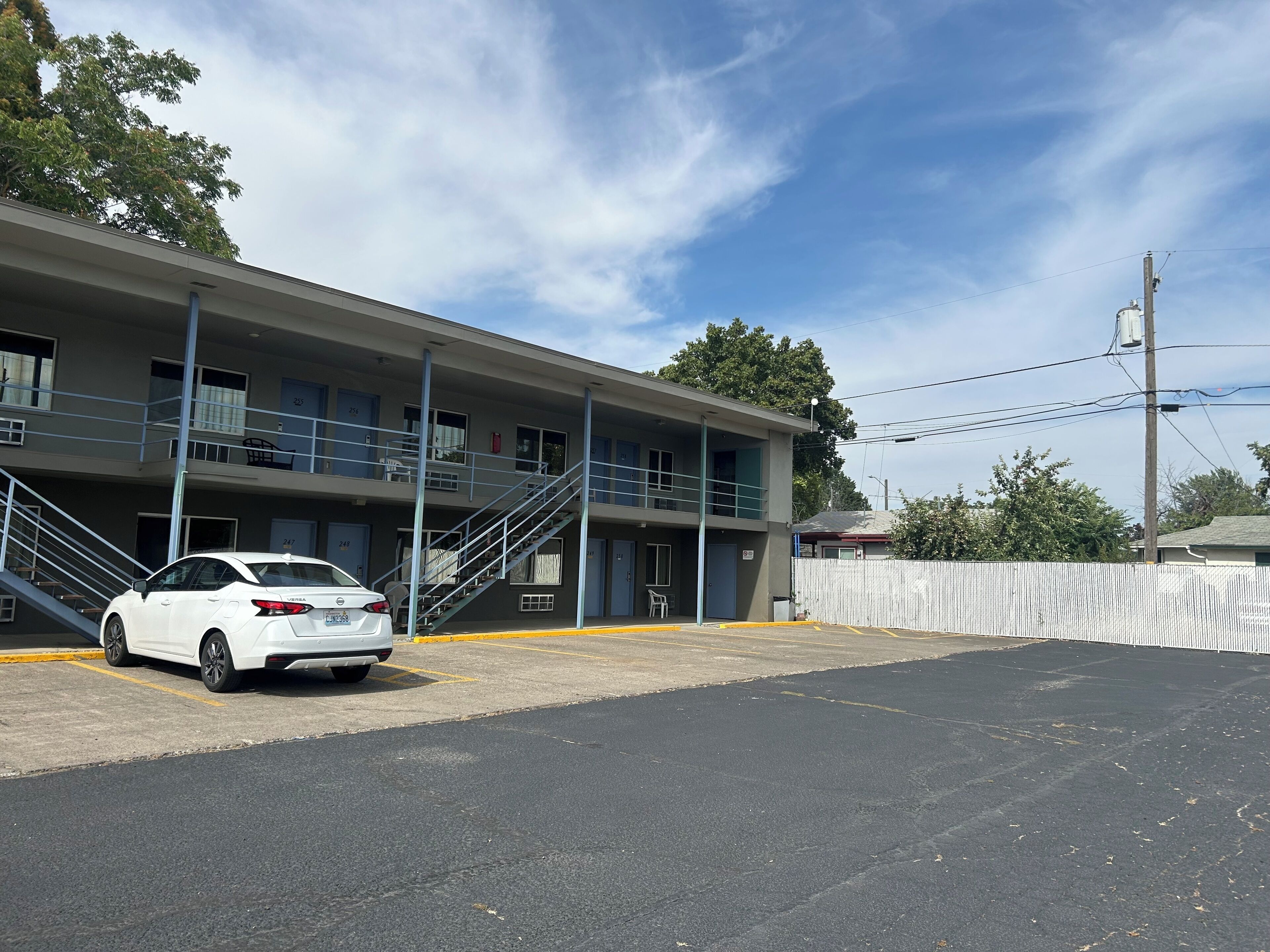 A two-story motel with a white car parked in the driveway.