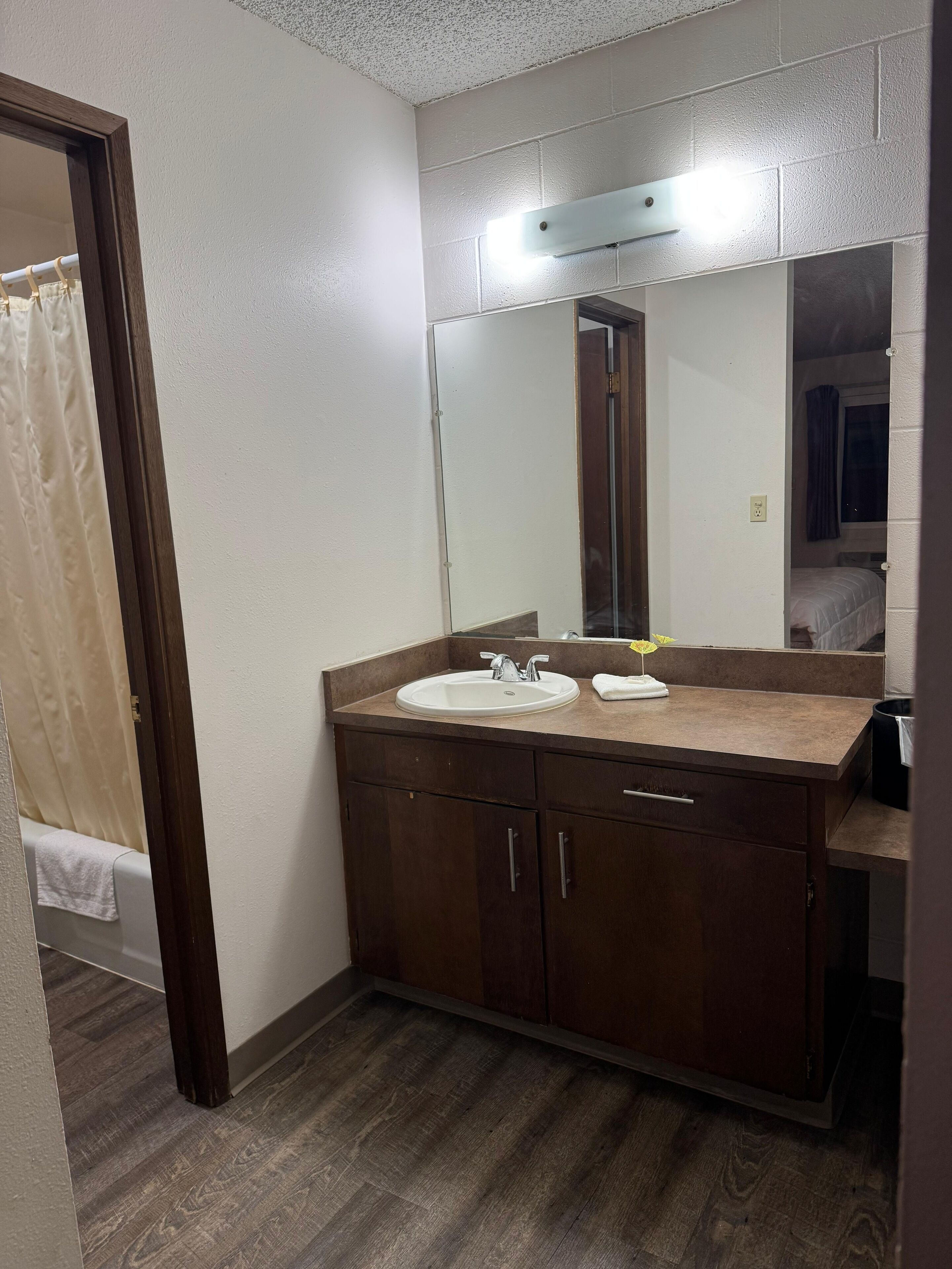 Un baño con tocador de madera, dos lavamanos, un espejo y una cortina de ducha.