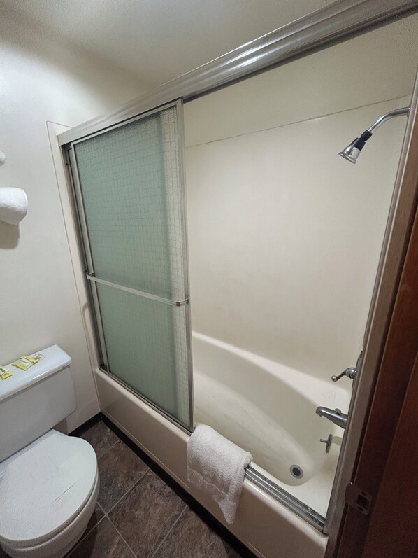 Un baño con ducha de vidrio, inodoro y una toalla colgada en la pared.