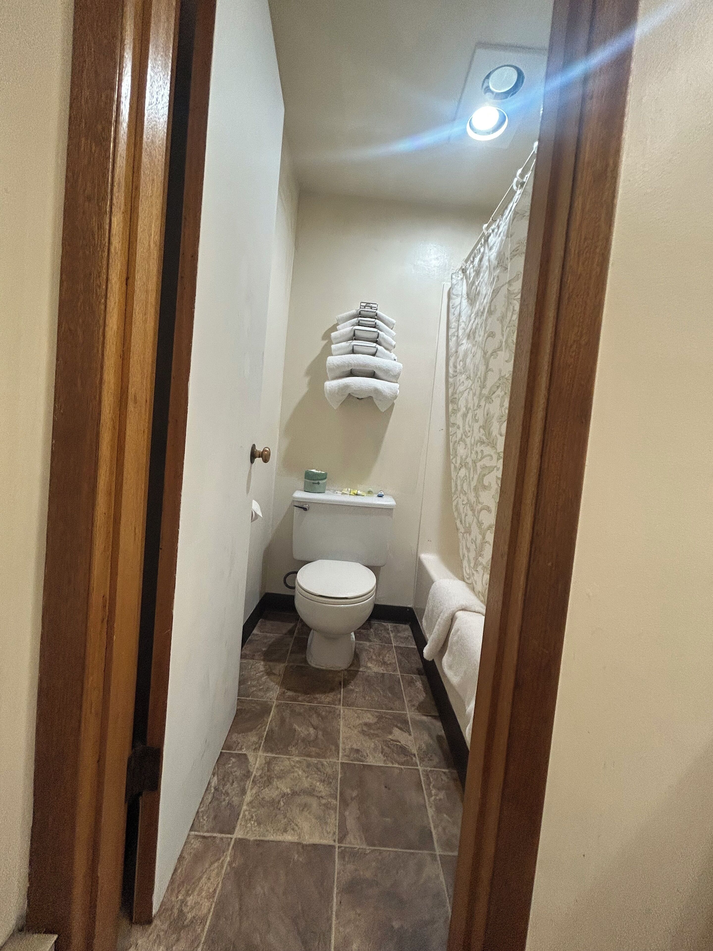 Un baño estrecho con inodoro, toallero y cortina de ducha.