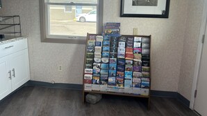 A room with a window, a framed picture, a display rack with travel guides, and a white cabinet. - Capri Motel By Belvilla Walla Walla US 12 (Walla Walla)