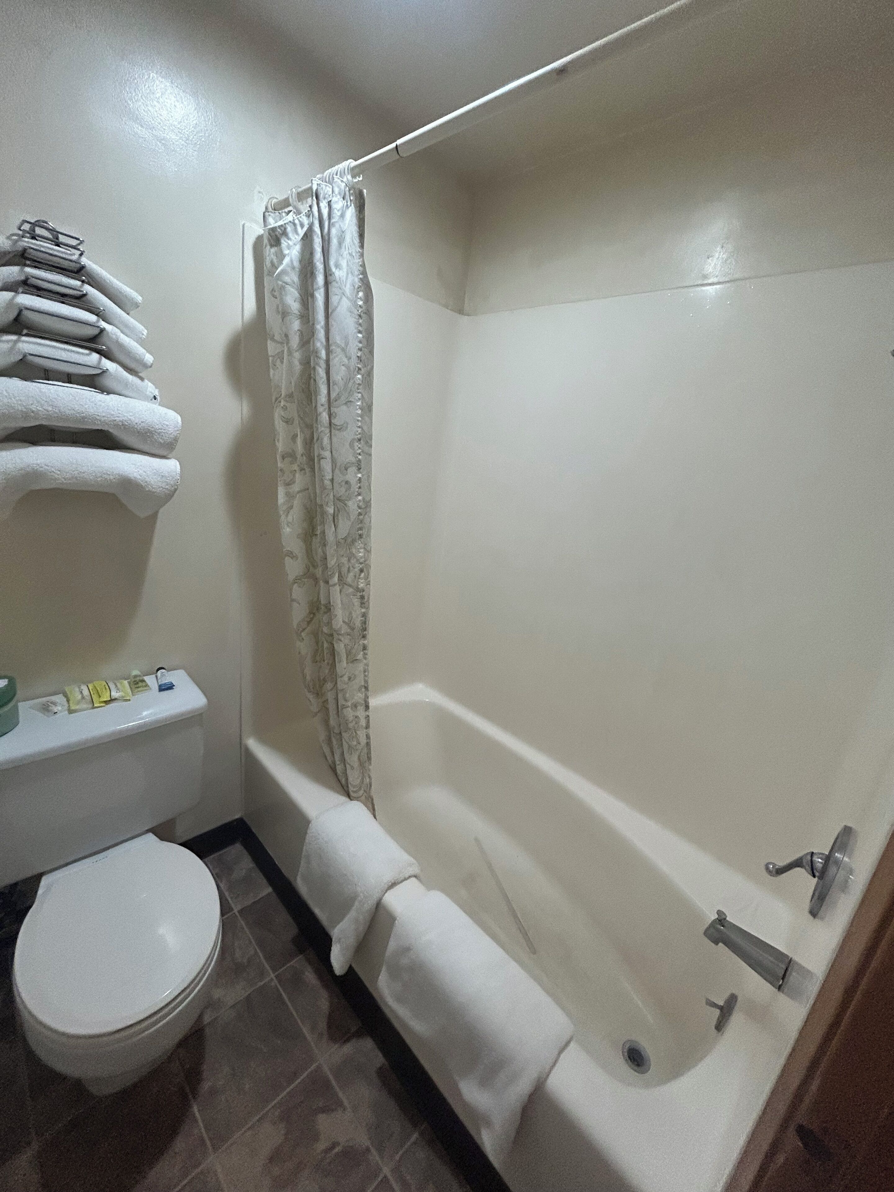Een badkamer met een bad, toilet en een handdoekrek met opgevouwen handdoeken.