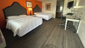 A hotel room with two beds, a desk, a chair, a TV, and a bathroom visible through an open door. - Capri Motel By Belvilla Walla Walla US 12 (Walla Walla)