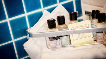 A bathroom shelf with toiletries including a bottle of shampoo and a box labeled "Verbenac".